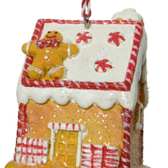 Χριστουγεννιάτικο στολίδι σε σχήμα gingerbread house. Το σπίτι είναι διακοσμημένο με άσπρο-κόκκινο "γλάσο". Στην κάτασπρη δίρριχτη στέγη είναι ξαπλωμένο ένα gingerbread ανθρωπάκι και ζαχαρωτά.