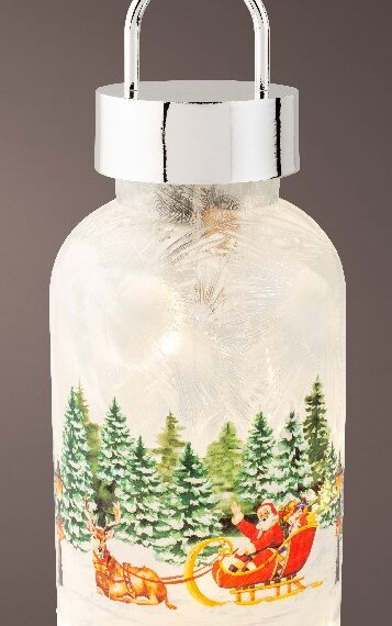 Χριστουγεννιάτικο φωτιζόμενο φαναράκι με τον Άγιο Βασίλη στο έλκηθρο του να μας χαιρετάει. Π΄σω του υπάρχουν πολλά χιονισμένα έλατα. Είναι διαθέσιμο και με χιονάνθρωπο. Είναι διαθέσιμο και με κοκκινολάιμη. Φωτάκια LED σε ζεστή λευκή απόχρωση ημέρας. Διάμετρος: 10cm. Ύψος:23cm