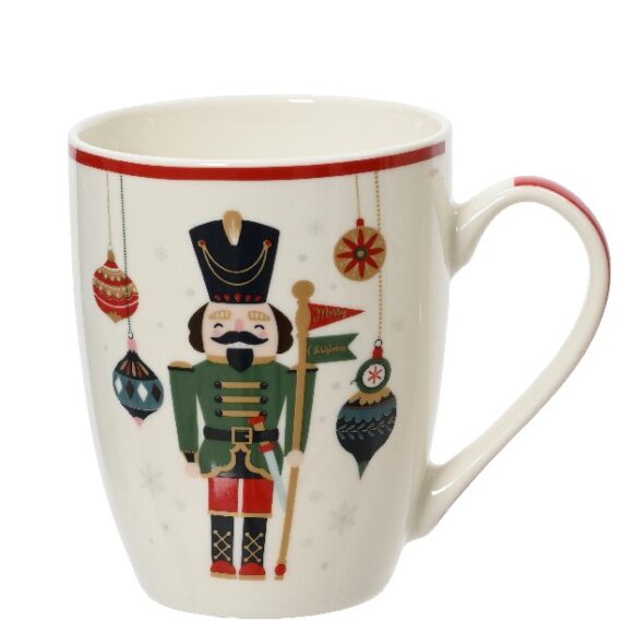 Χριστουγεννιάτικη κούπα καρυοθραύστης με σημαιούλα. Ο καρυοθραύστης φοράει πράσινη-κόκκινη στολή και κρατάει μια χρυσή σημαιούλα. Πίσω του κρέμονται πολυχρωμες χριστουγεννιάτικες μπάλες. Η βάση της κούπας είναι λευκή. Διατίθεται και με καρυθραύστη με γλειφιτζούρι 8,5 x 8,2 x 10,5cm