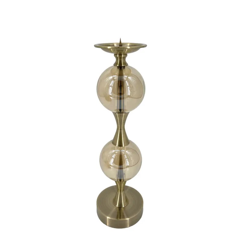Κηροπήγιο ύψους 42 cm και διαμέτρου 12 cm, κατασκευασμένο από ανθεκτικό μέταλλο σε κομψή μπρονζέ απόχρωση. Διαθέτει δύο διακοσμητικές γυάλινες μπάλες σε διάφανη απόχρωση, που προσθέτουν φινέτσα και ελαφρότητα στον σχεδιασμό. Κατάλληλο για κλασικά κεριά (όχι ρεσώ), αποτελεί ιδανική επιλογή για τραπέζι, μπουφέ ή κεντρικό διακοσμητικό σε ειδικές περιστάσεις.